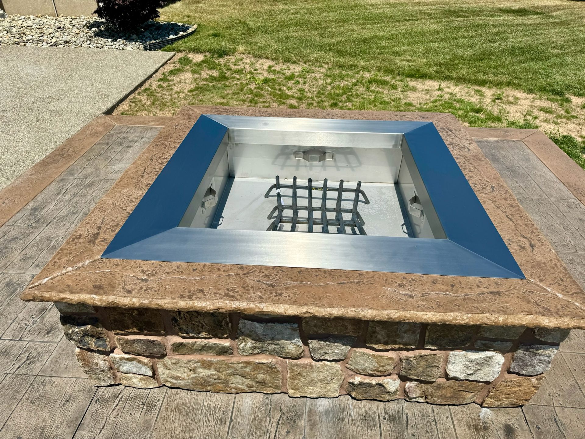 Stone fire pit with metal insert and decorative stone border on a patio.