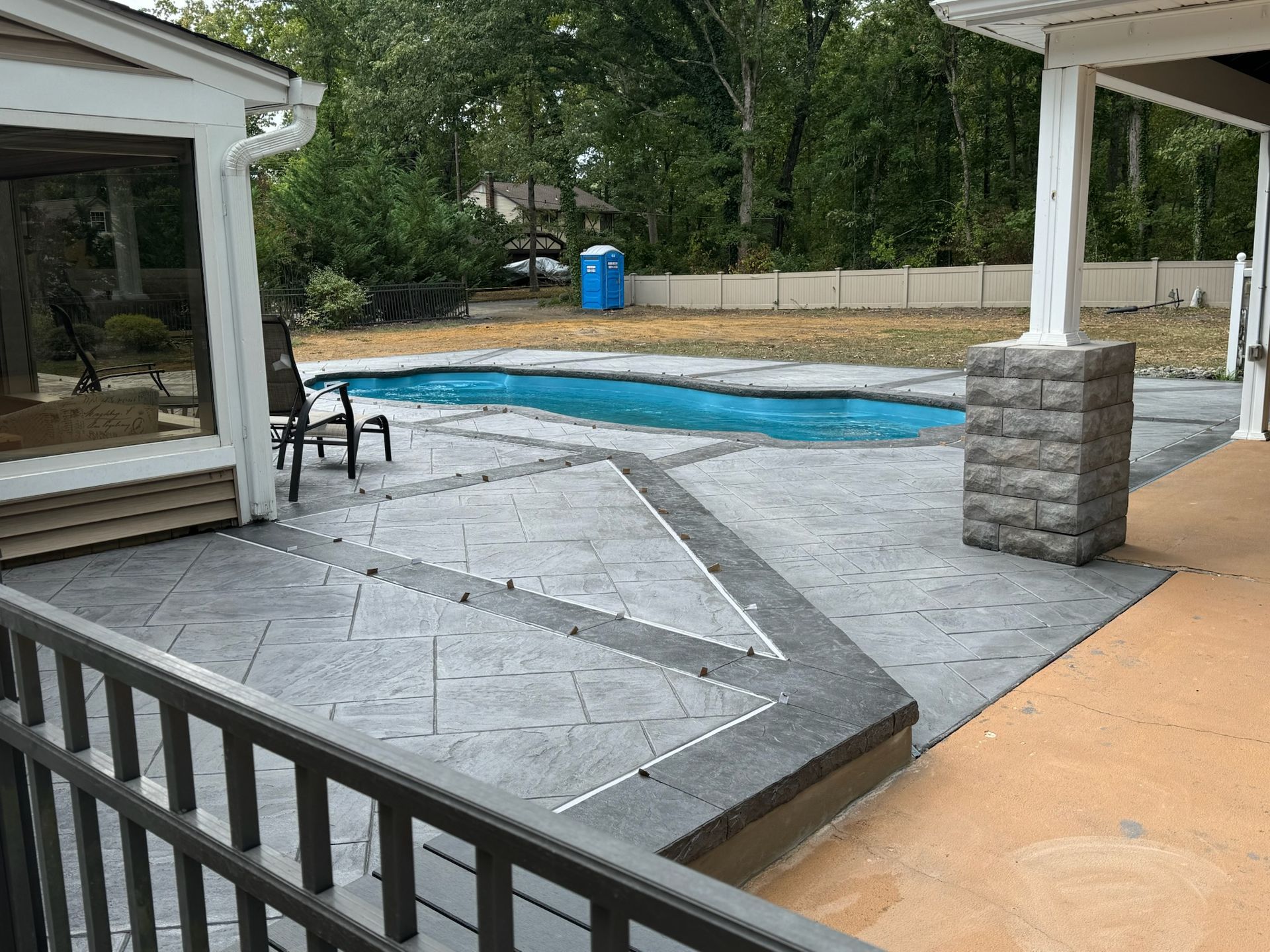 Backyard with stamped concrete patio, pool, and a covered porch area.