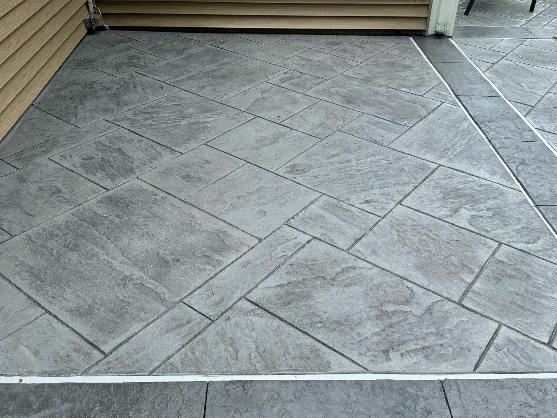 Gray stamped concrete patio with a geometric stone pattern.