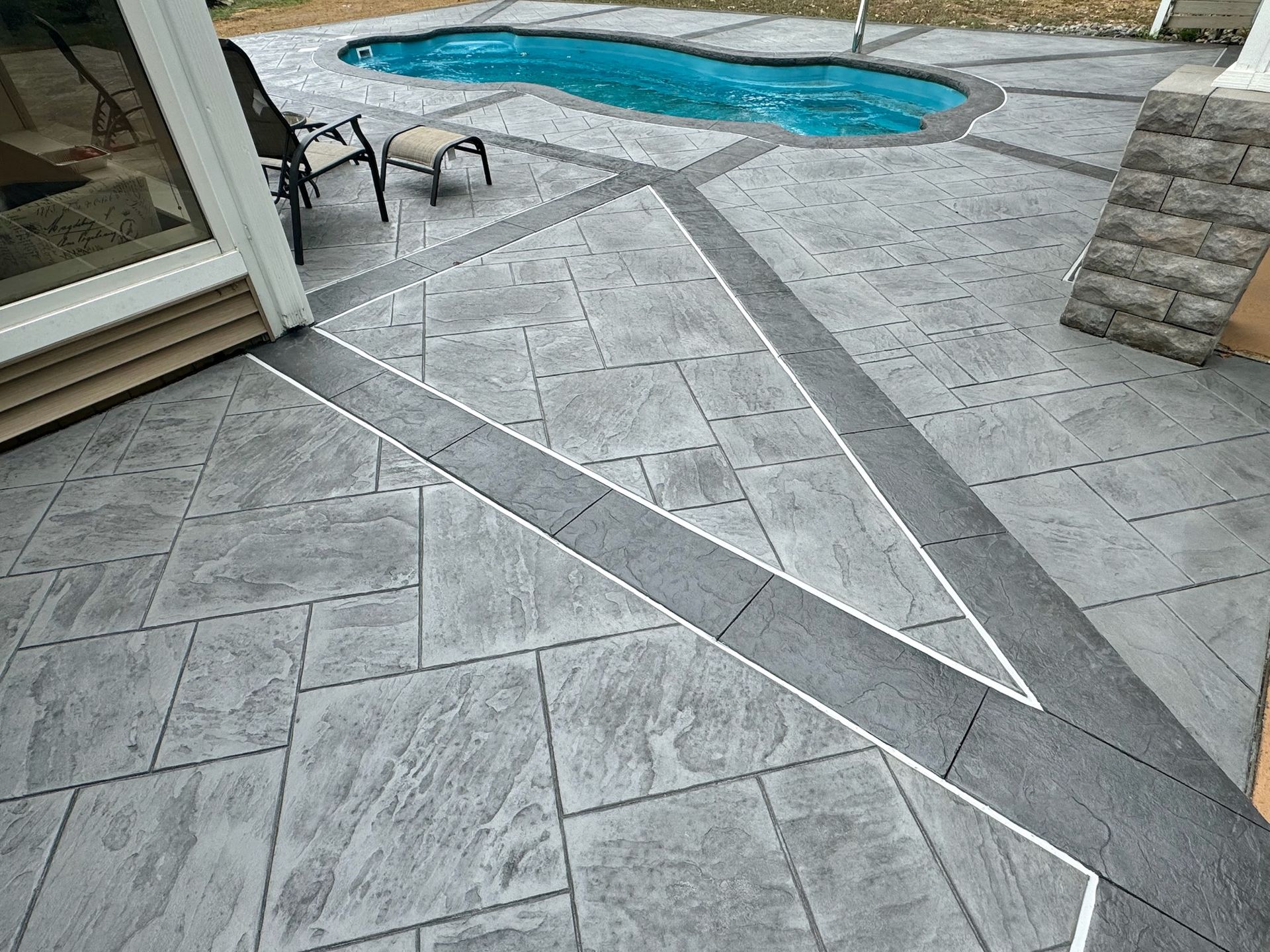 Gray patio with a pool, stone paving, and dark grey accents.