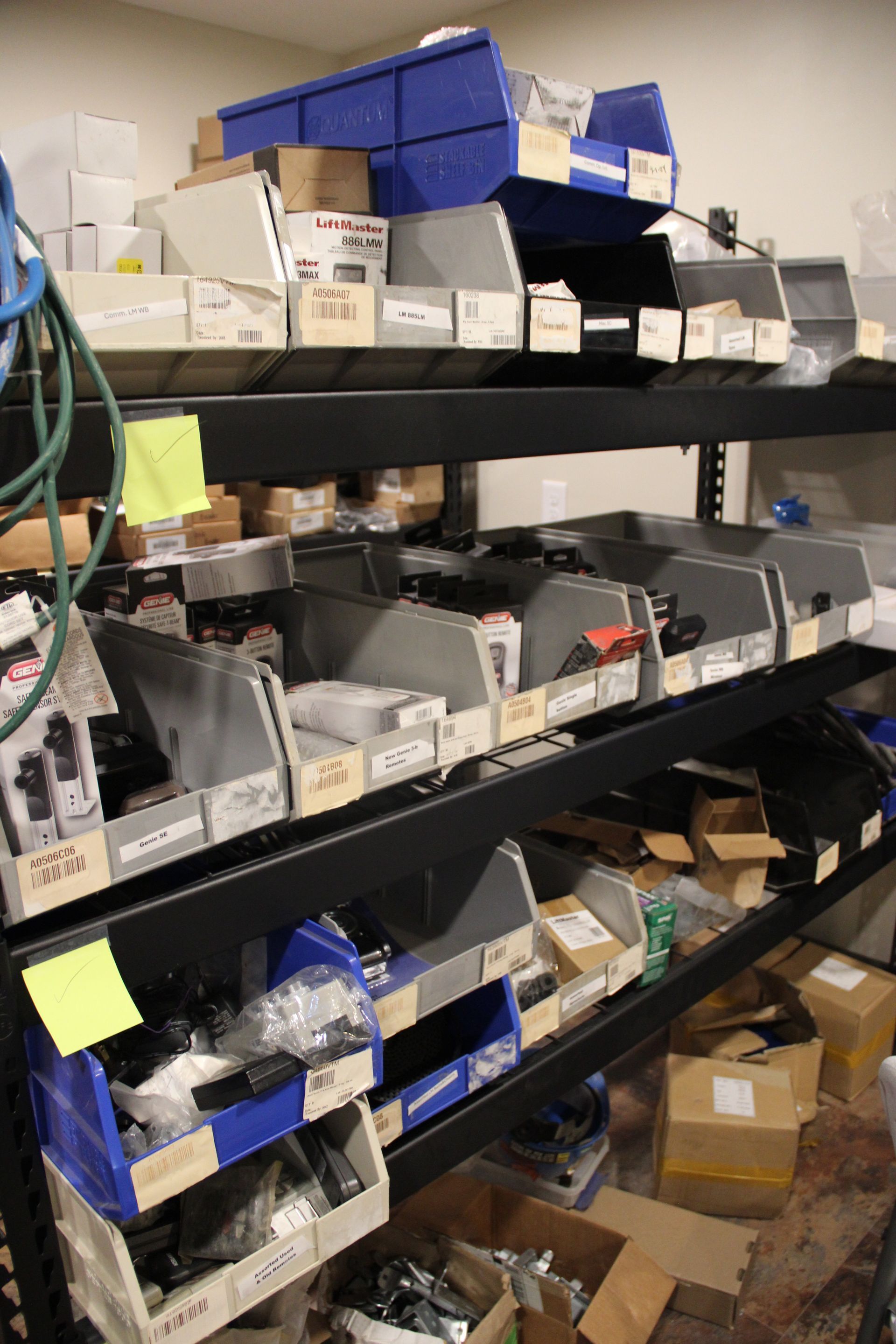 Shelves of assorted storage bins and boxes in a cluttered supply room