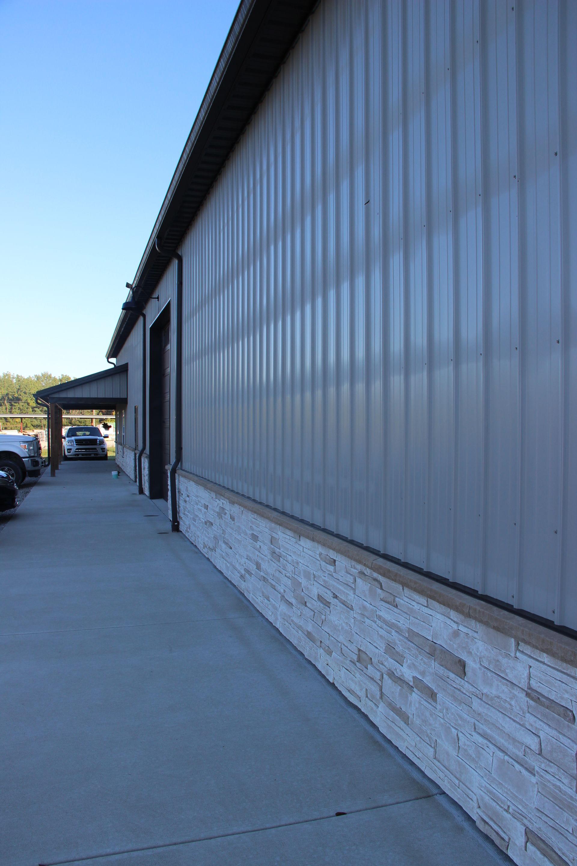 Long metal building wall along a concrete sidewalk on a sunny day