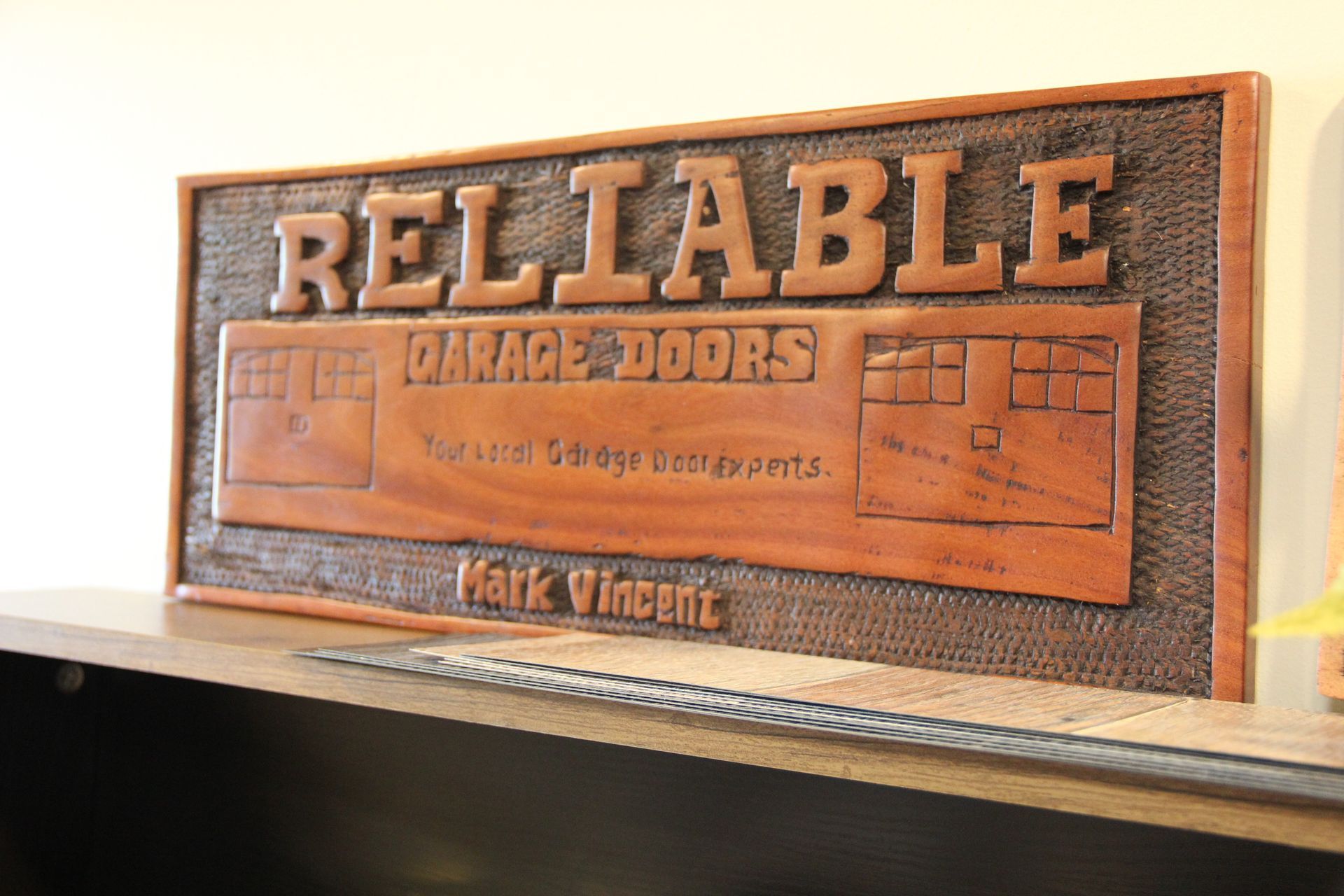 Wooden carved sign reading “RELIABLE” on a shelf, in warm brown tones.