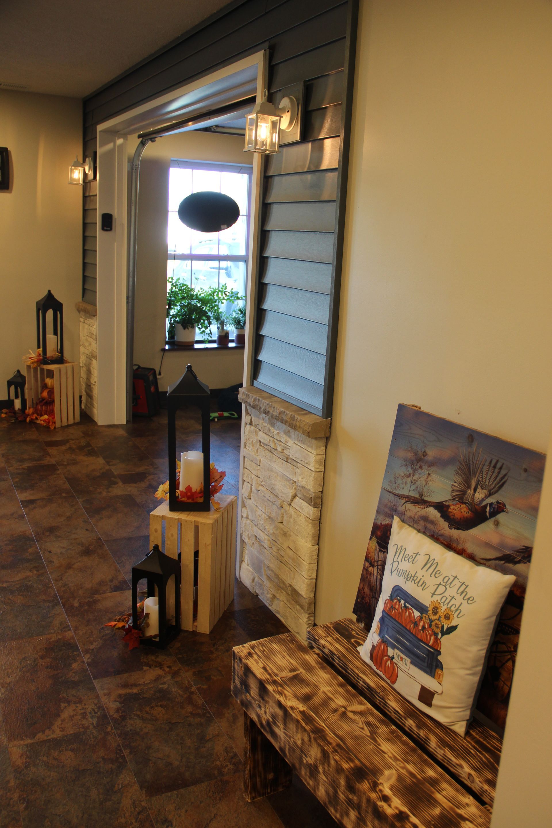 Hallway with lanterns, rustic bench, and framed art leaning against the wall near an open doorway