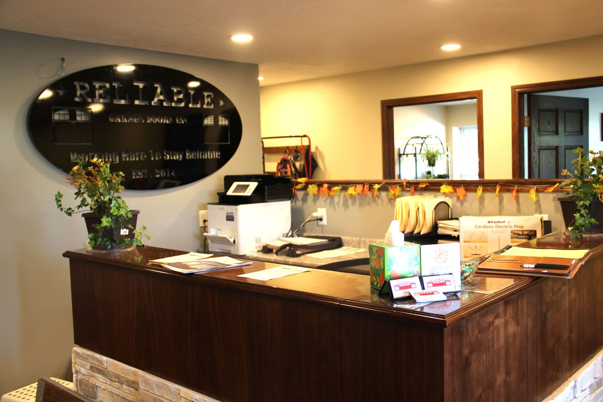 Bright reception counter in a warmly lit salon or spa with a black oval sign and product display.
