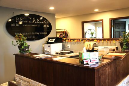 Warmly lit hotel reception desk with a dark wood counter, flowers, and a “RELIABLE” wall sign