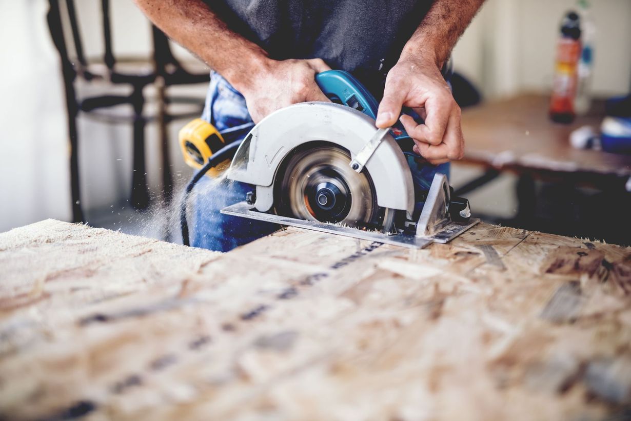 A person uses a circular saw to cut a piece of wood in a workshop.