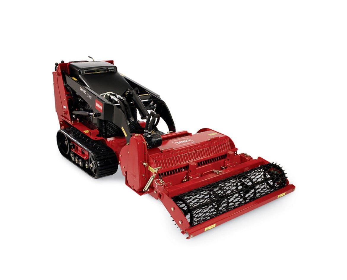 Red and black Toro compact utility loader with brush cutter attachment, on a white background.