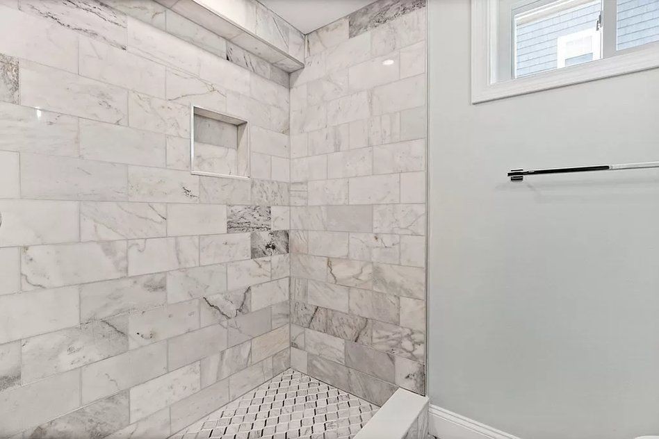 A bathroom with marble tiles and a walk in shower.