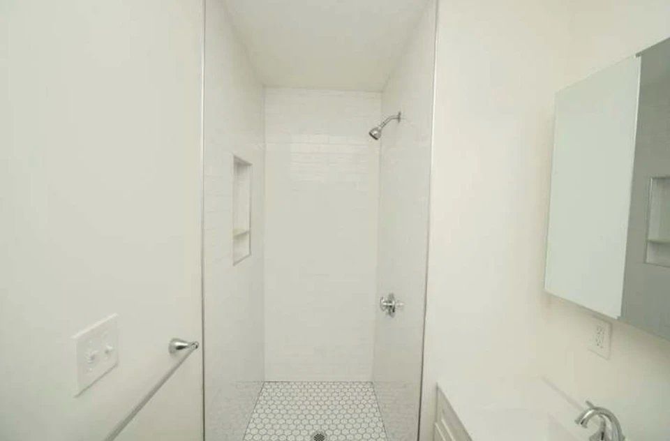 A bathroom with a walk in shower and a sink.