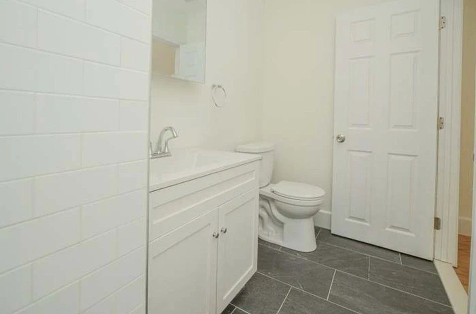 A bathroom with a sink, toilet, and tile floor.