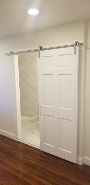 A bedroom with a sliding barn door leading to a bathroom.