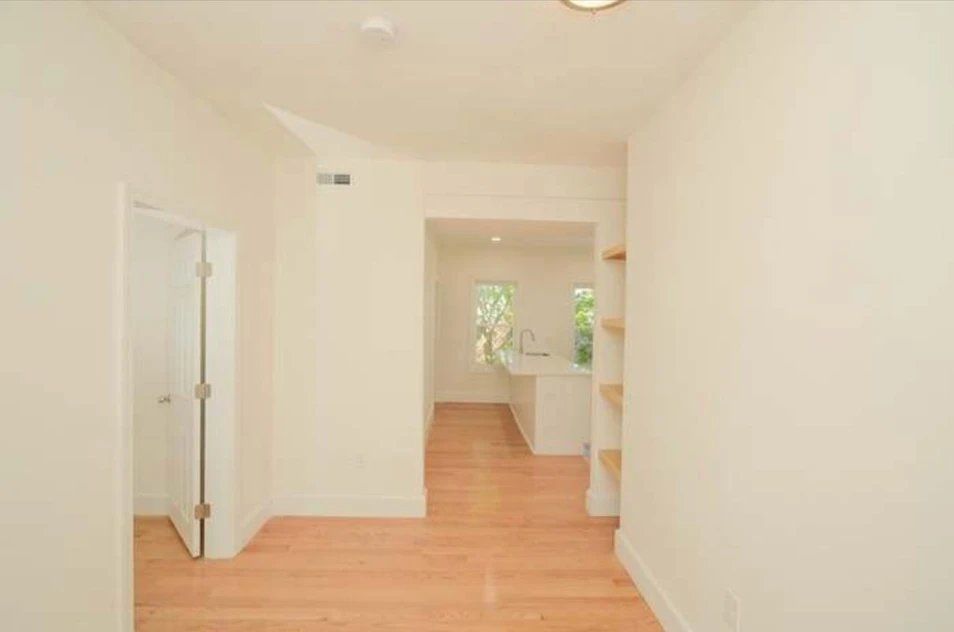 An empty room with hardwood floors and white walls.