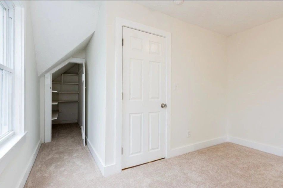 An empty bedroom with a closet and a window
