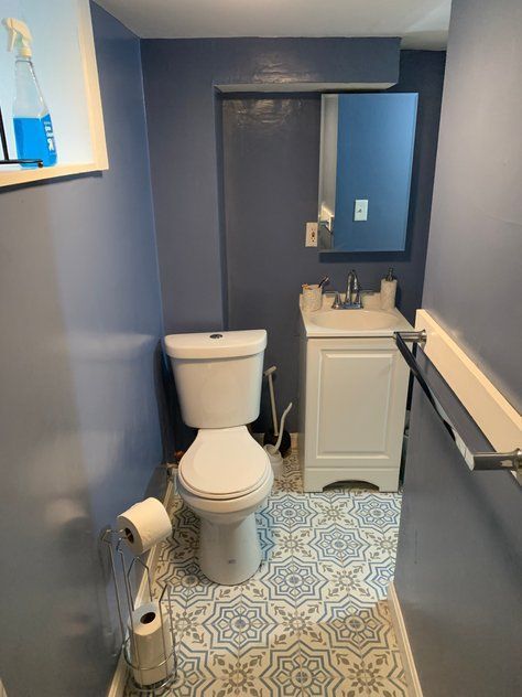 A bathroom with a toilet, sink and mirror.