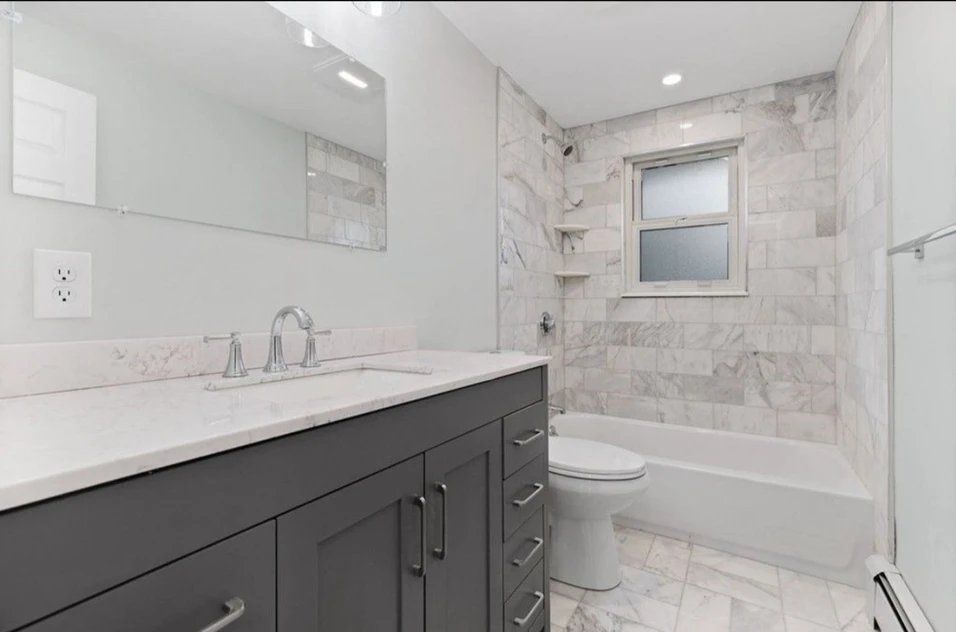 A bathroom with a sink, toilet, tub and mirror.