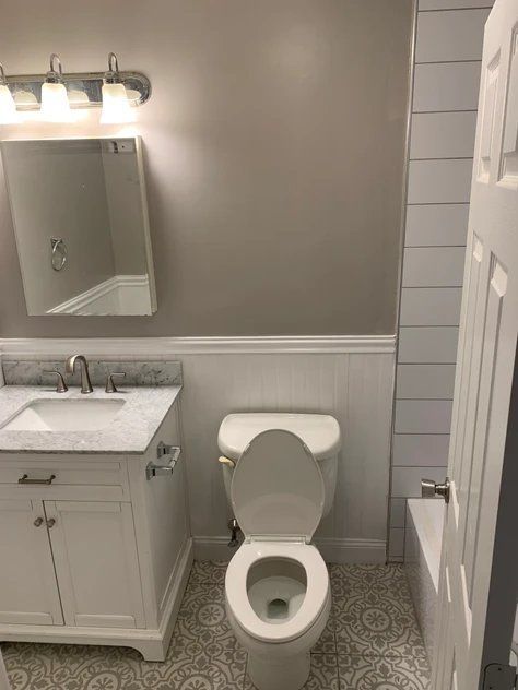 A bathroom with a toilet, sink, mirror and bathtub.