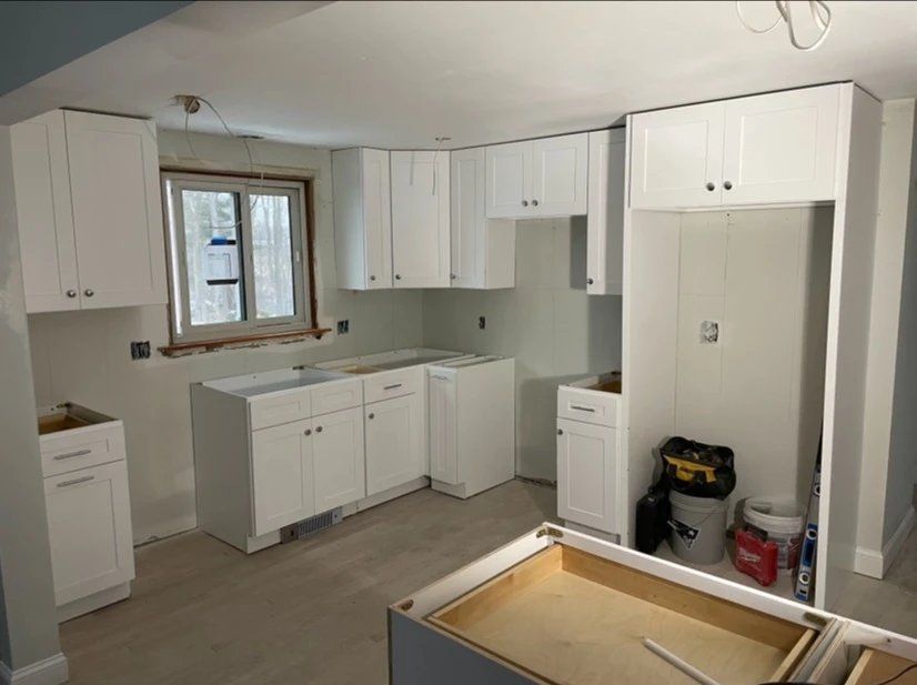 A kitchen under construction with white cabinets and a window
