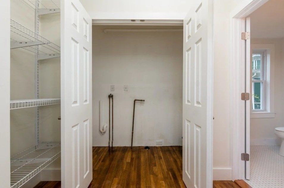 A laundry room with wooden floors and white doors.