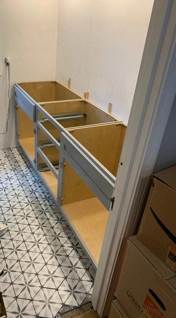 A bathroom vanity is being built in a room with boxes on the floor.