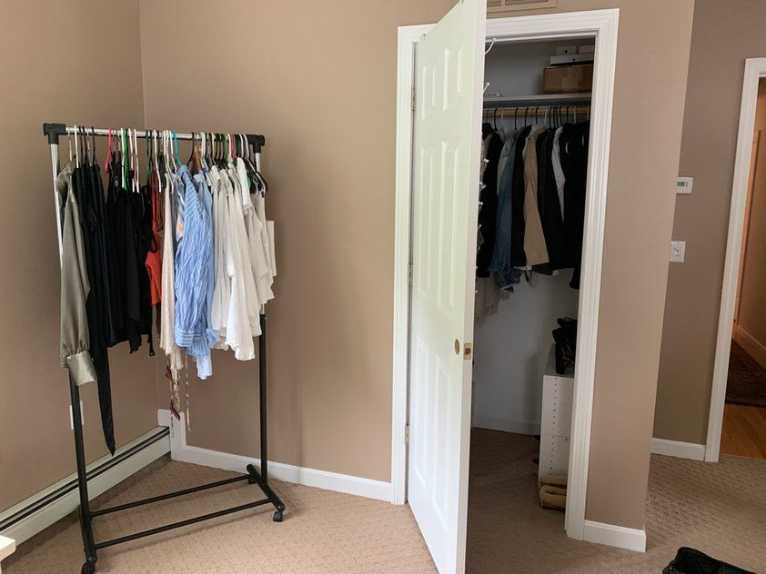 A room with a closet and a rack of clothes.