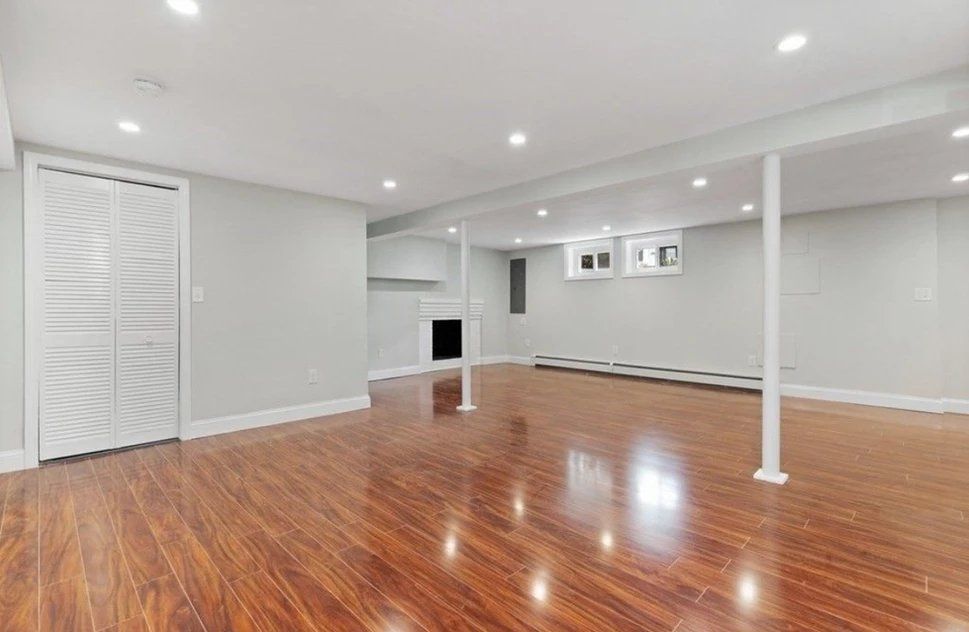 A neat-looking empty basement with hardwood floors and white walls.