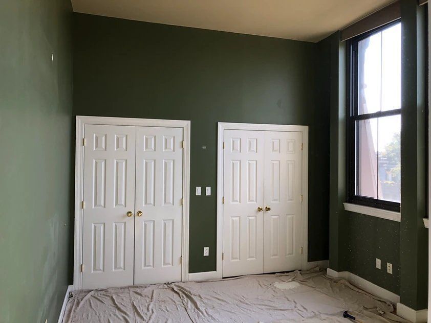 An empty room with green walls and white doors