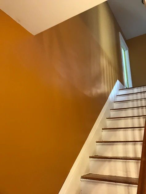 A staircase with a yellow wall and white steps