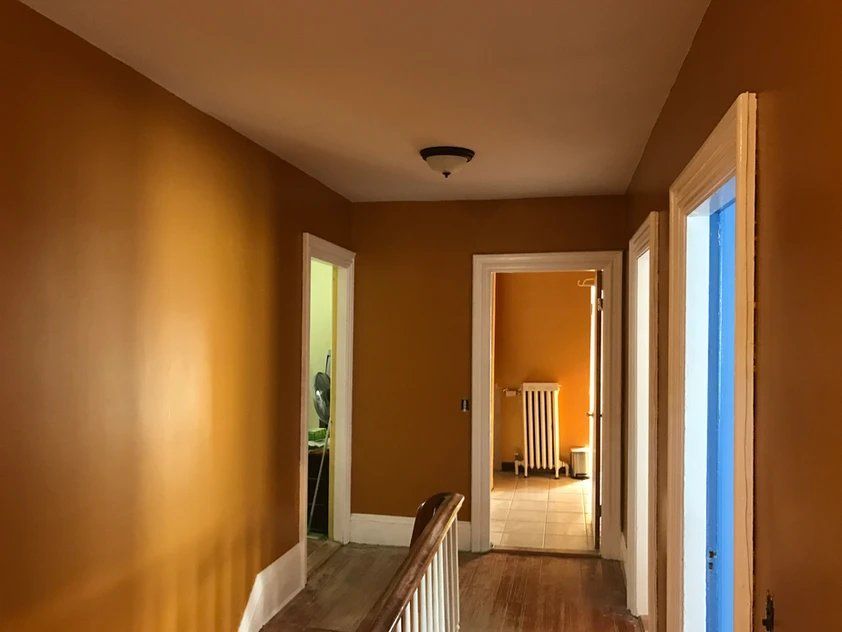 A hallway with yellow walls and a blue door