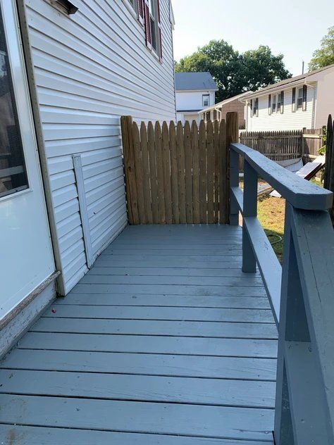 A wooden deck with a wooden fence in front of a house.