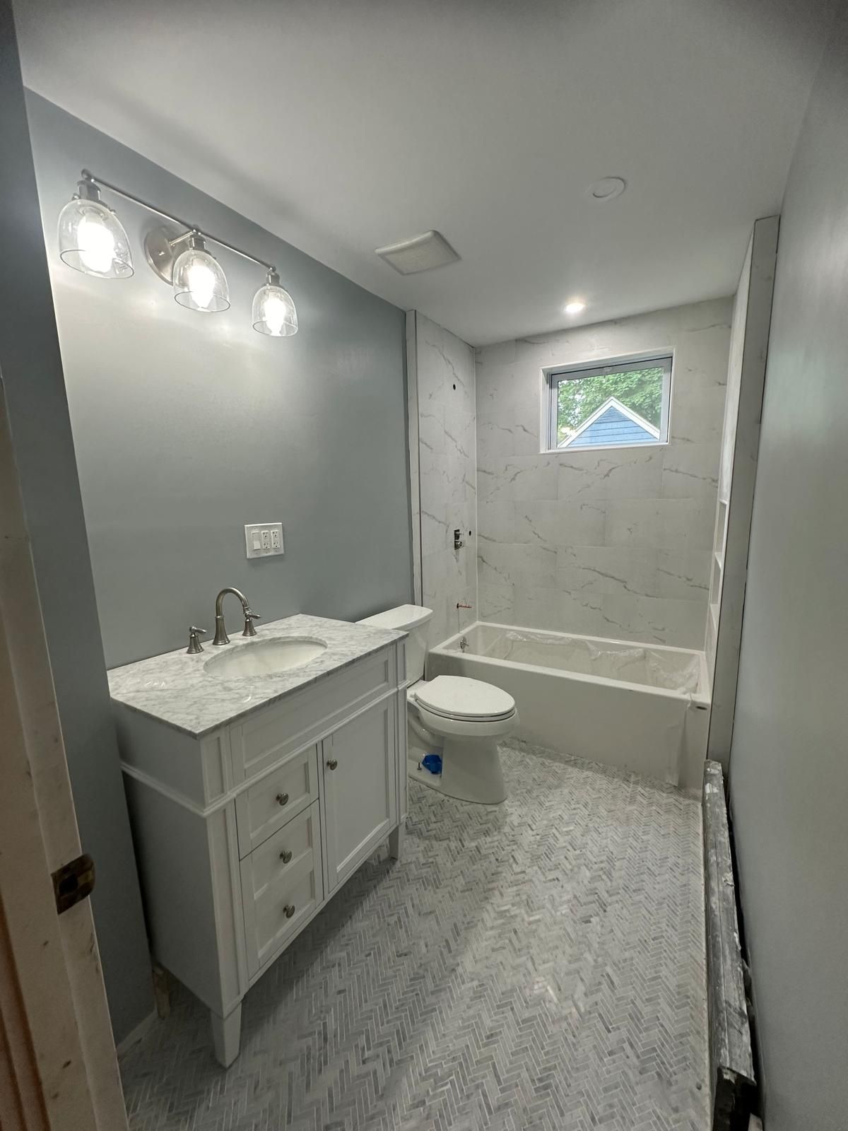 A bathroom with a sink, toilet, tub and window.
