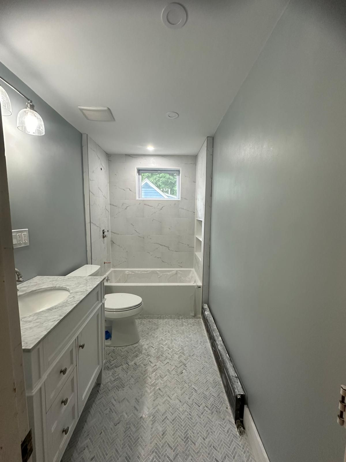 A picture of a bathroom with a sink, toilet, tub, and window.