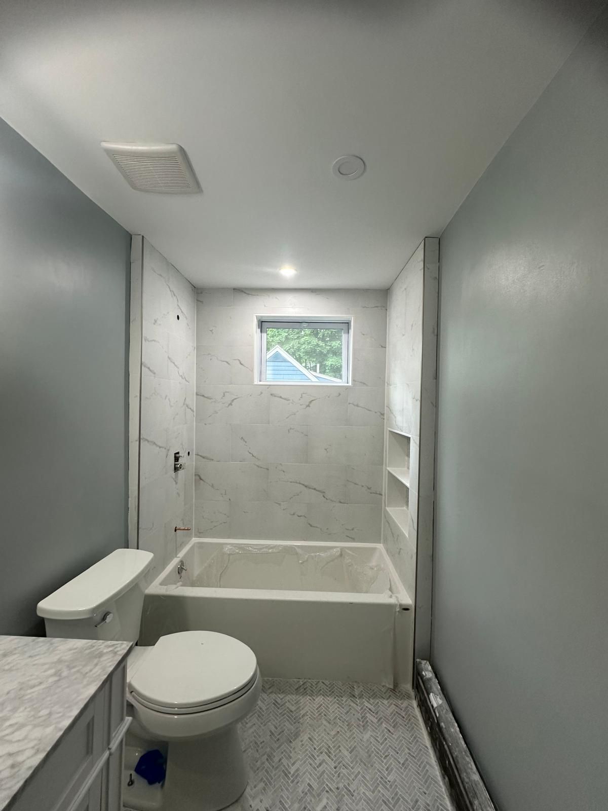 An image of a bathroom with a toilet, tub, and window.