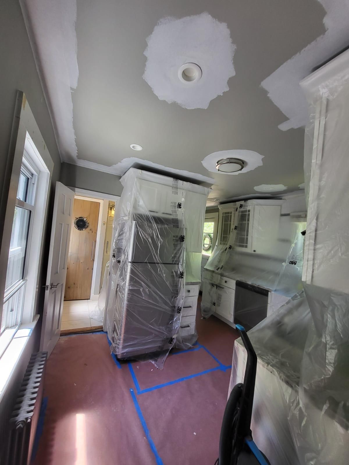 A kitchen with a refrigerator wrapped in plastic.