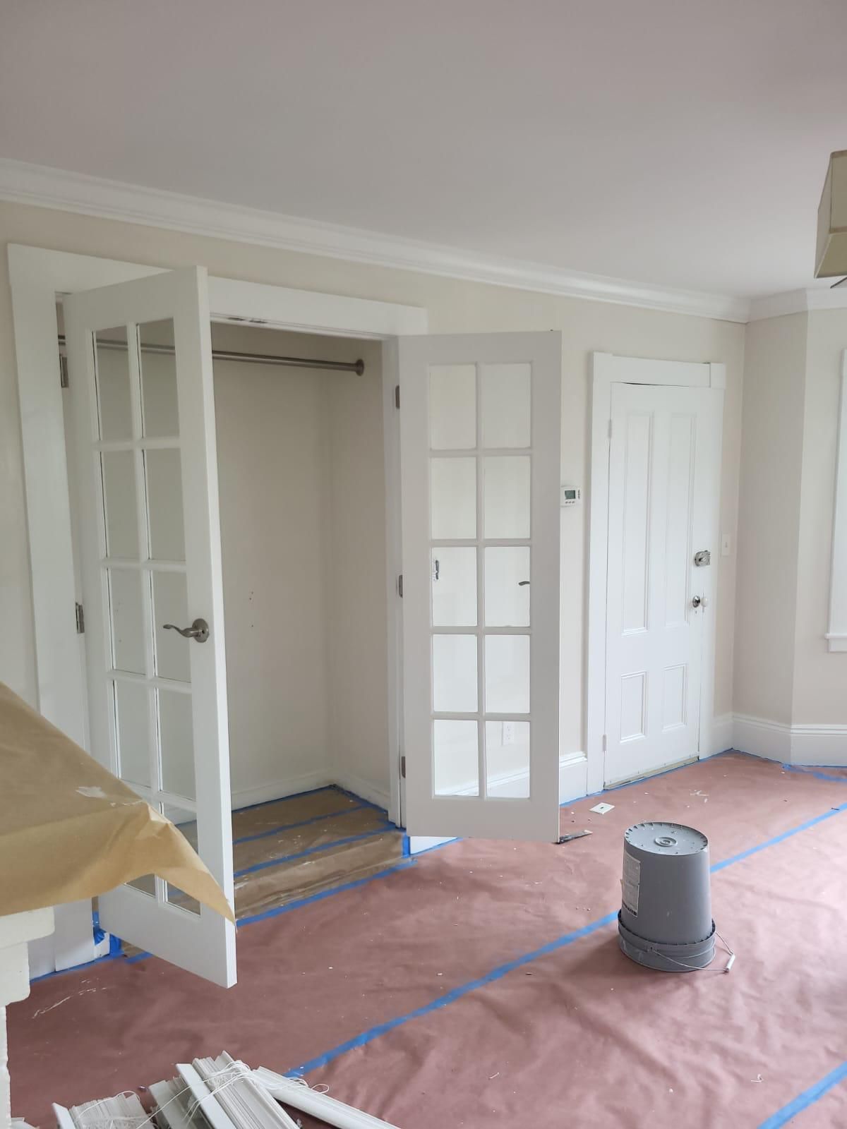 An empty room with french doors and a bucket on the floor