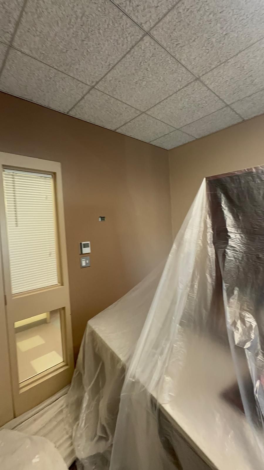 A room with a table and a door covered in plastic.