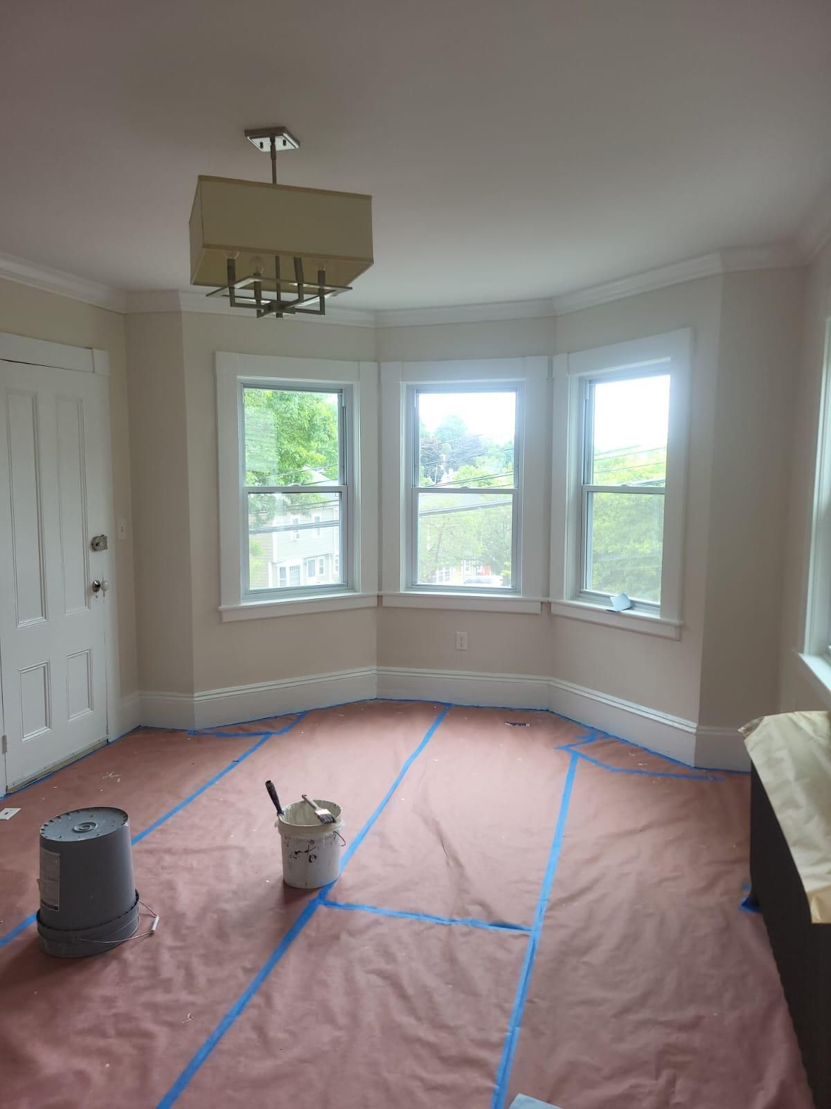 An empty room with a bucket of paint on the floor
