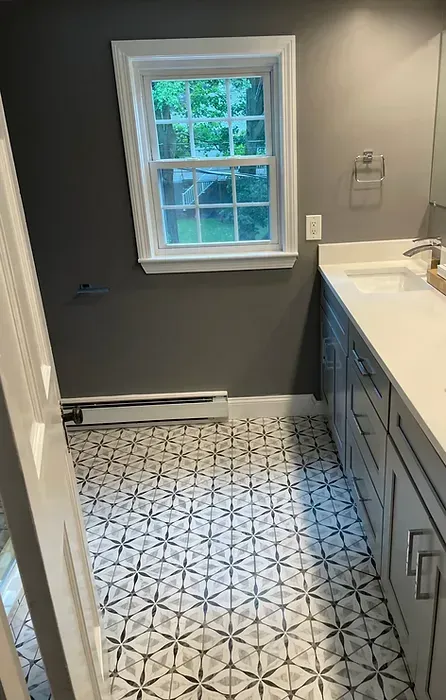 A bathroom with a sink , cabinets , and a window.