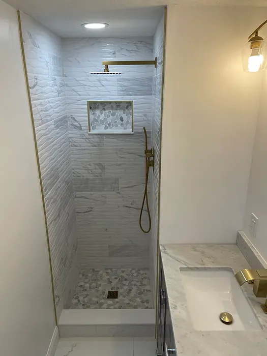 A bathroom with a walk in shower and a sink.