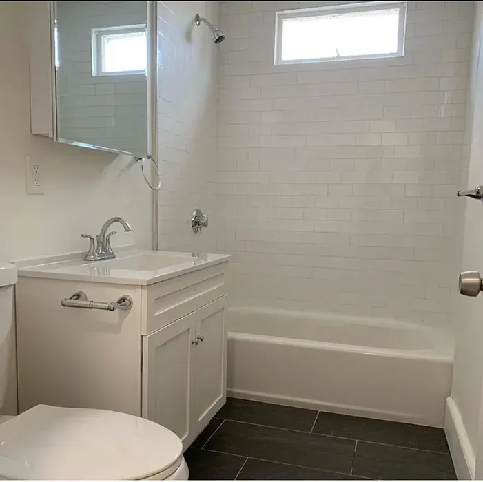 A bathroom with a toilet , sink , tub and mirror.