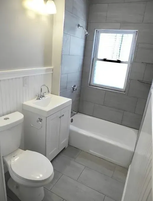 A bathroom with a toilet , sink and bathtub.