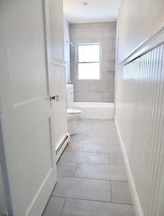A bathroom with a toilet , tub and window