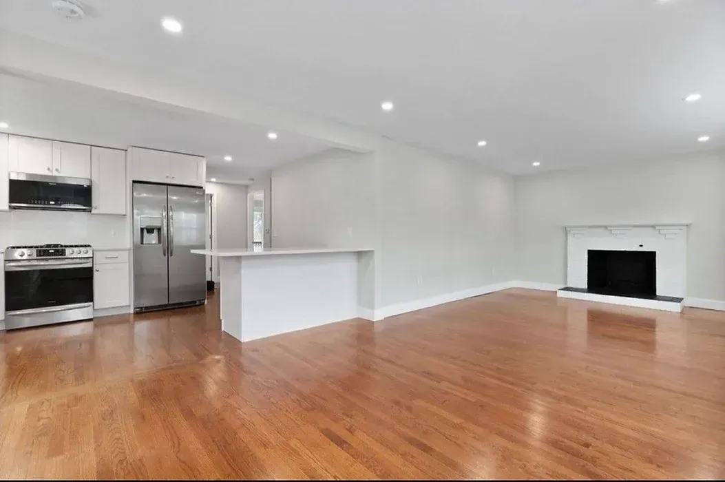 An empty living room with hardwood floors and a fireplace.