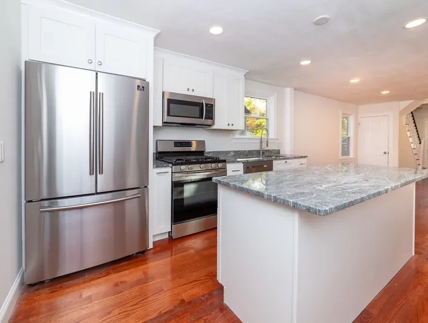 A kitchen with a stainless steel refrigerator , stove , and microwave.