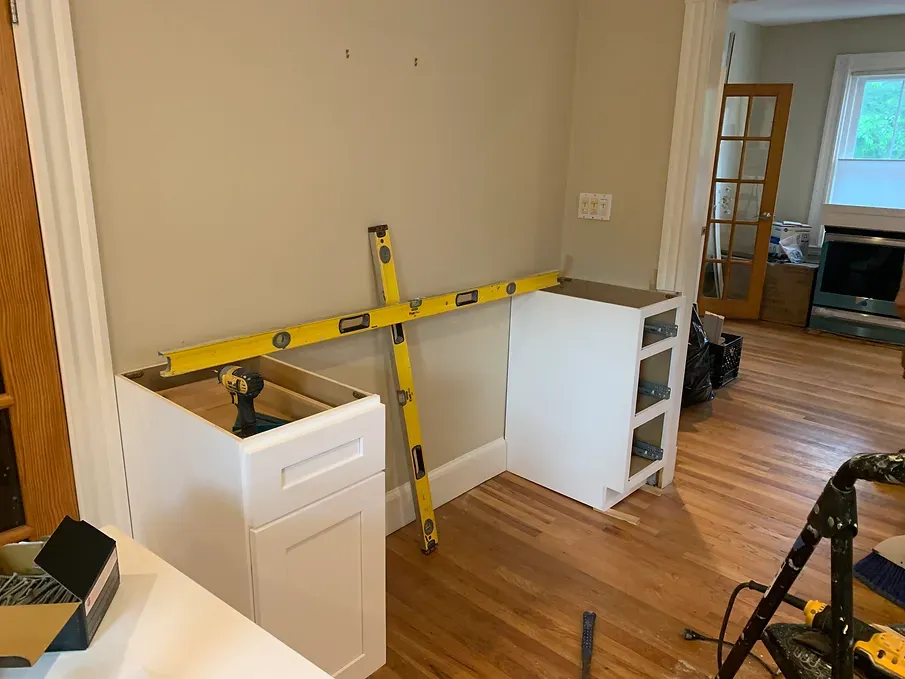 A person is measuring a cabinet with a level in a living room.