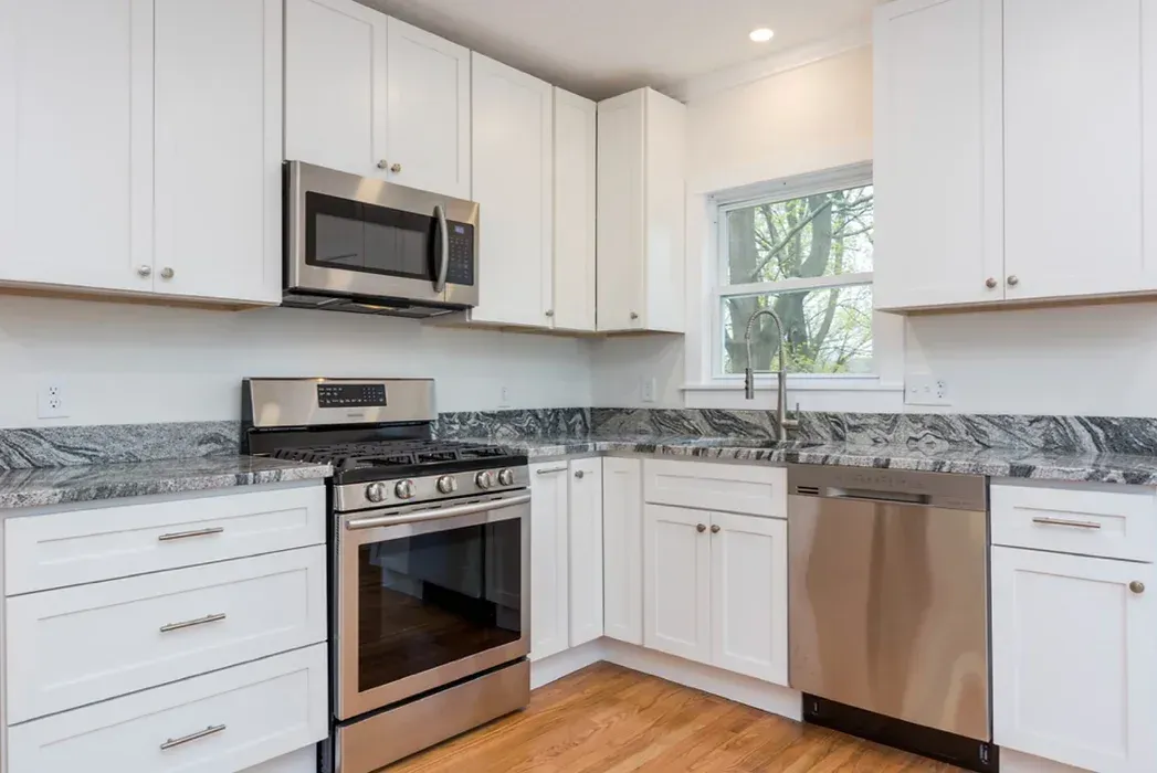A kitchen with stainless steel appliances and white cabinets.