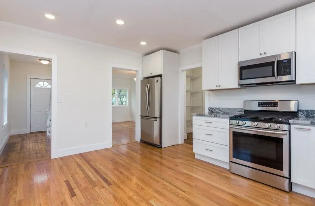 A kitchen with white cabinets , stainless steel appliances , and hardwood floors.