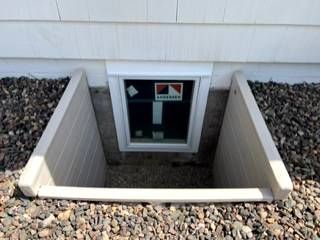 There is a window in the basement of a house.