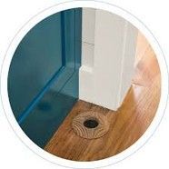 Blue door threshold with a floor drain beside a white wall on wood flooring