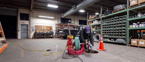 Warehouse floor with a worker near cleaning equipment, orange cones, and shelves of organized bins